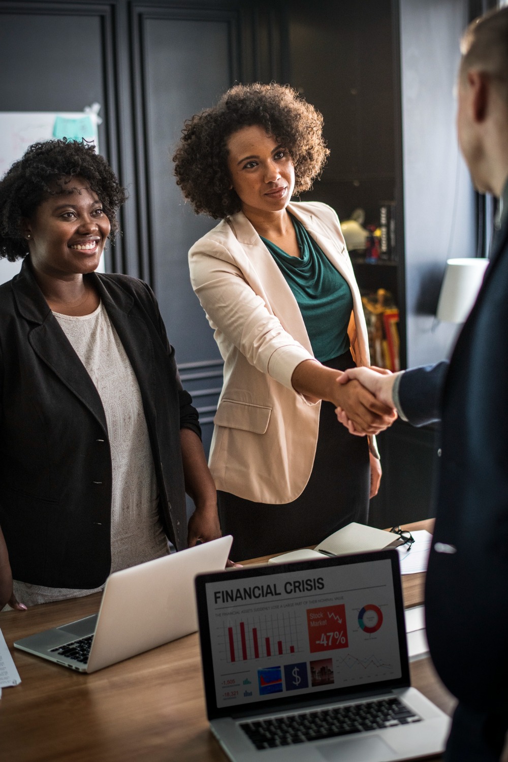 Two professionals shaking hands across a meeting table