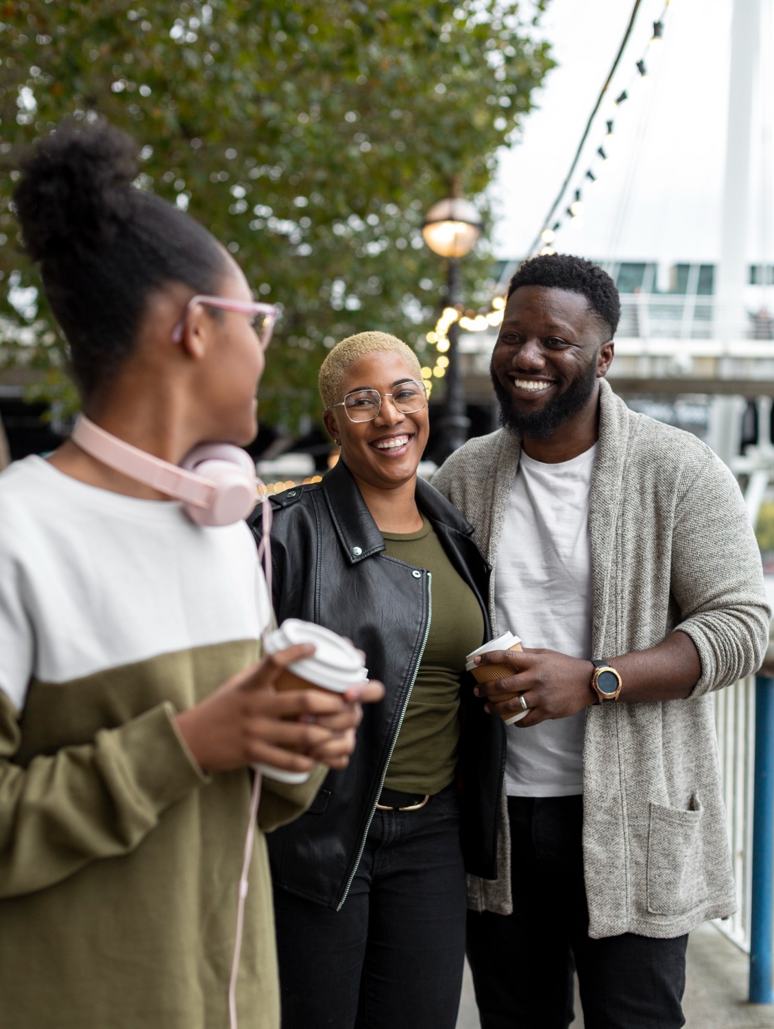 Three colleagues talking over coffee at an outdoor gathering